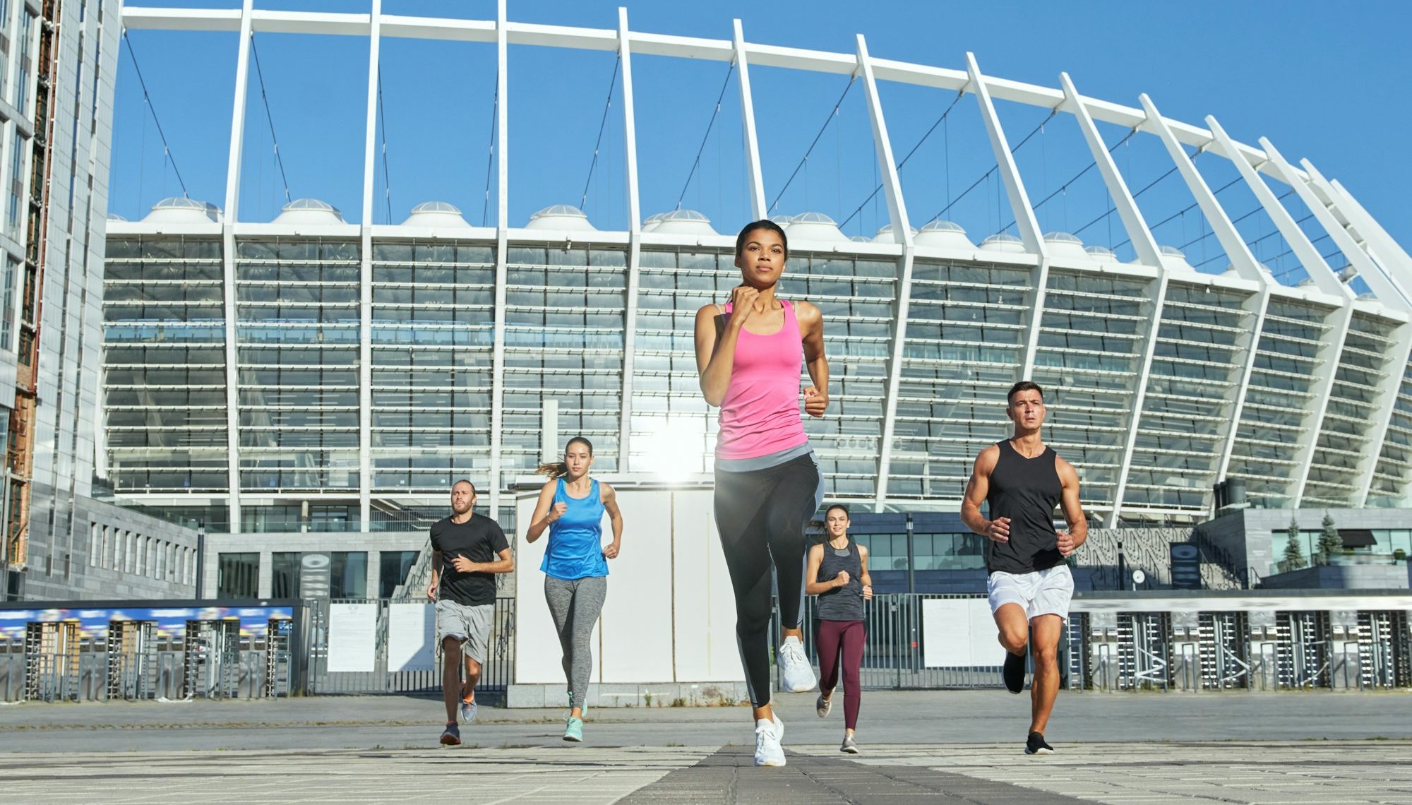 Multi racial young people running from stadium building