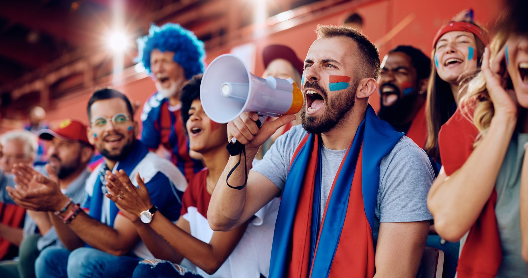 Sports fan shouting through megaphone during a match at the stadium.